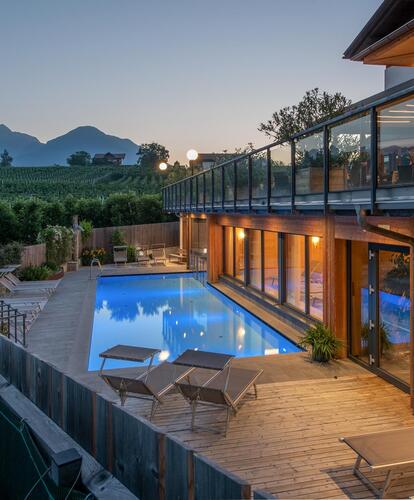 Abendaufnahme eines Hotels mit beleuchtetem Poolbereich, Terrasse und Panoramafe